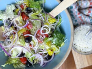Copycat Olive Garden Salad in a Blue Bowl with Wooden Servers