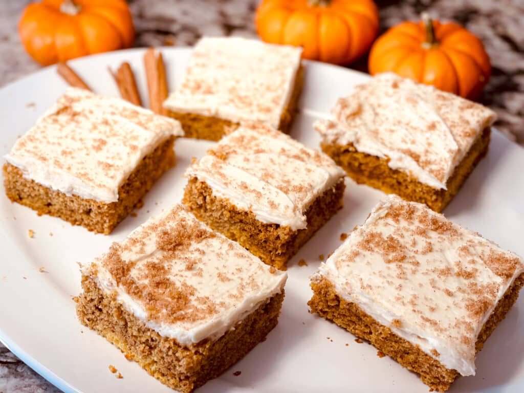 Pumpkin Bars with White Icing Cut in Squares on a White Plate