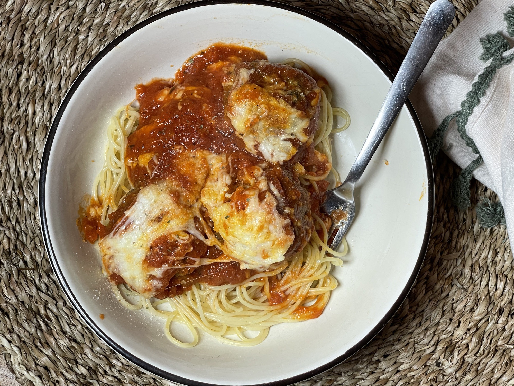 Spaghetti and meatballs in a light colored bowl with a fork