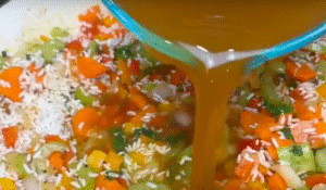 Pouring Broth into Jerk Chicken and Rice