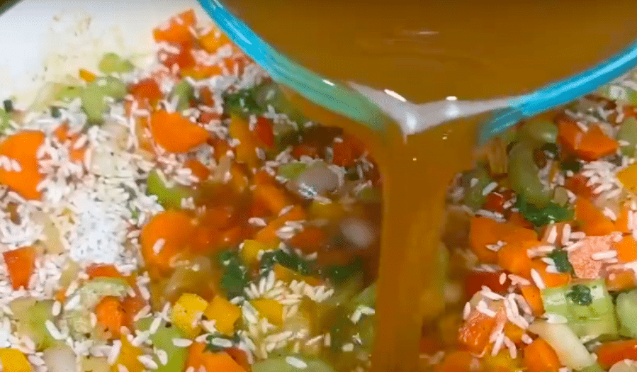 Pouring Broth into Jerk Chicken and Rice