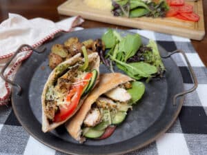 Caeser Pesto Chicken Pita on a Metal Plate with Salad and Potatoes