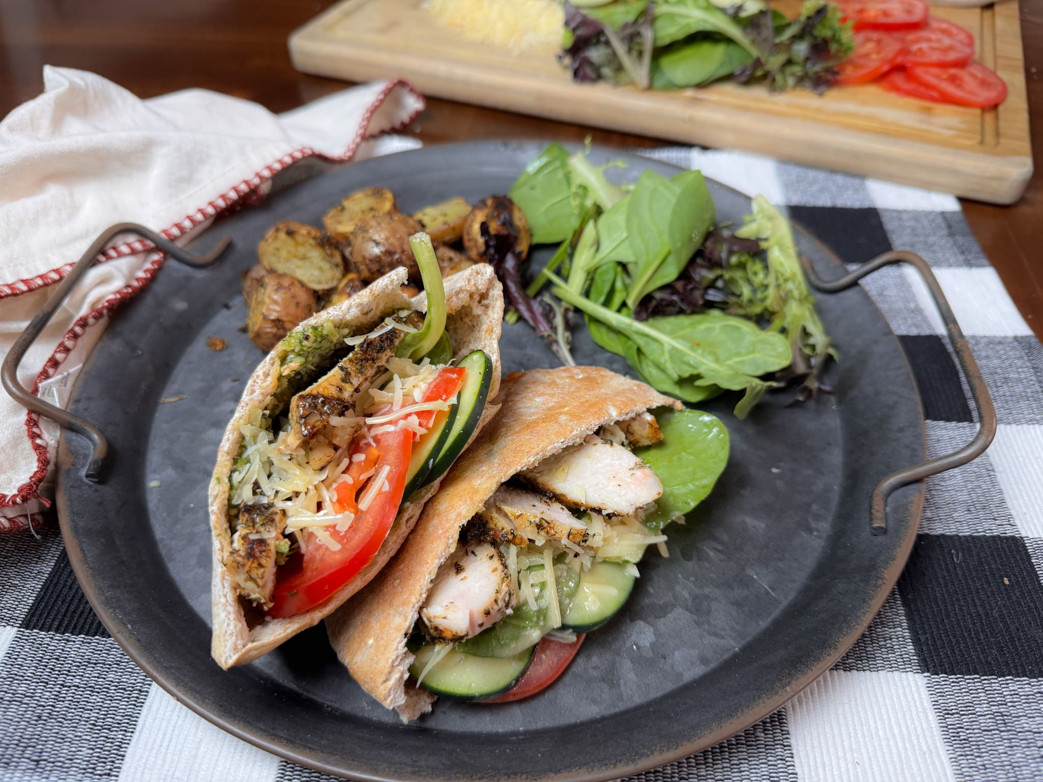 Caeser Pesto Chicken Pita On a metal plate with salad and potatoes