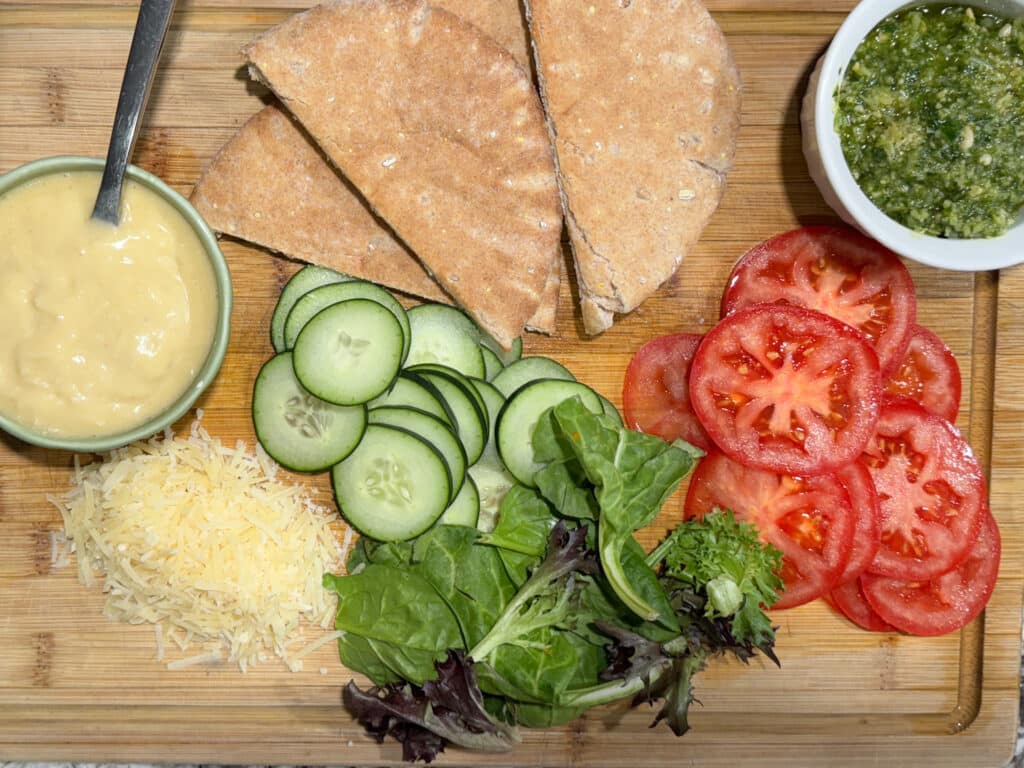 Sliced Cucumbers, Tomatoes, Lettuce, Pitas Cut in Half, Basil Pesto and Caeser Dressing