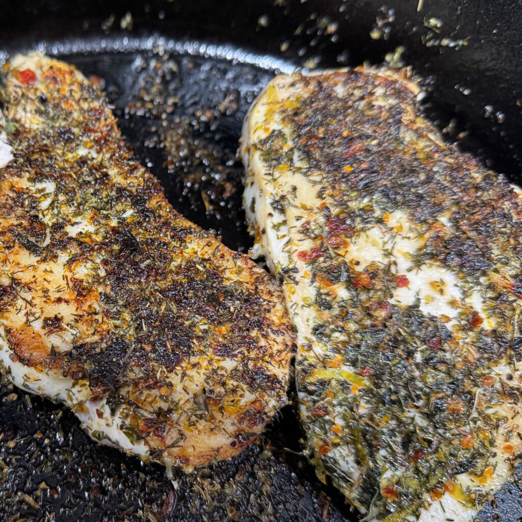 2 Chicken Breasts Fried in Cast Iron Skillet Covered in Greek Seasoning