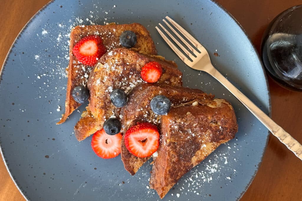Overhead Shot of Slices of French Toast on a Blue Plate with Fruit