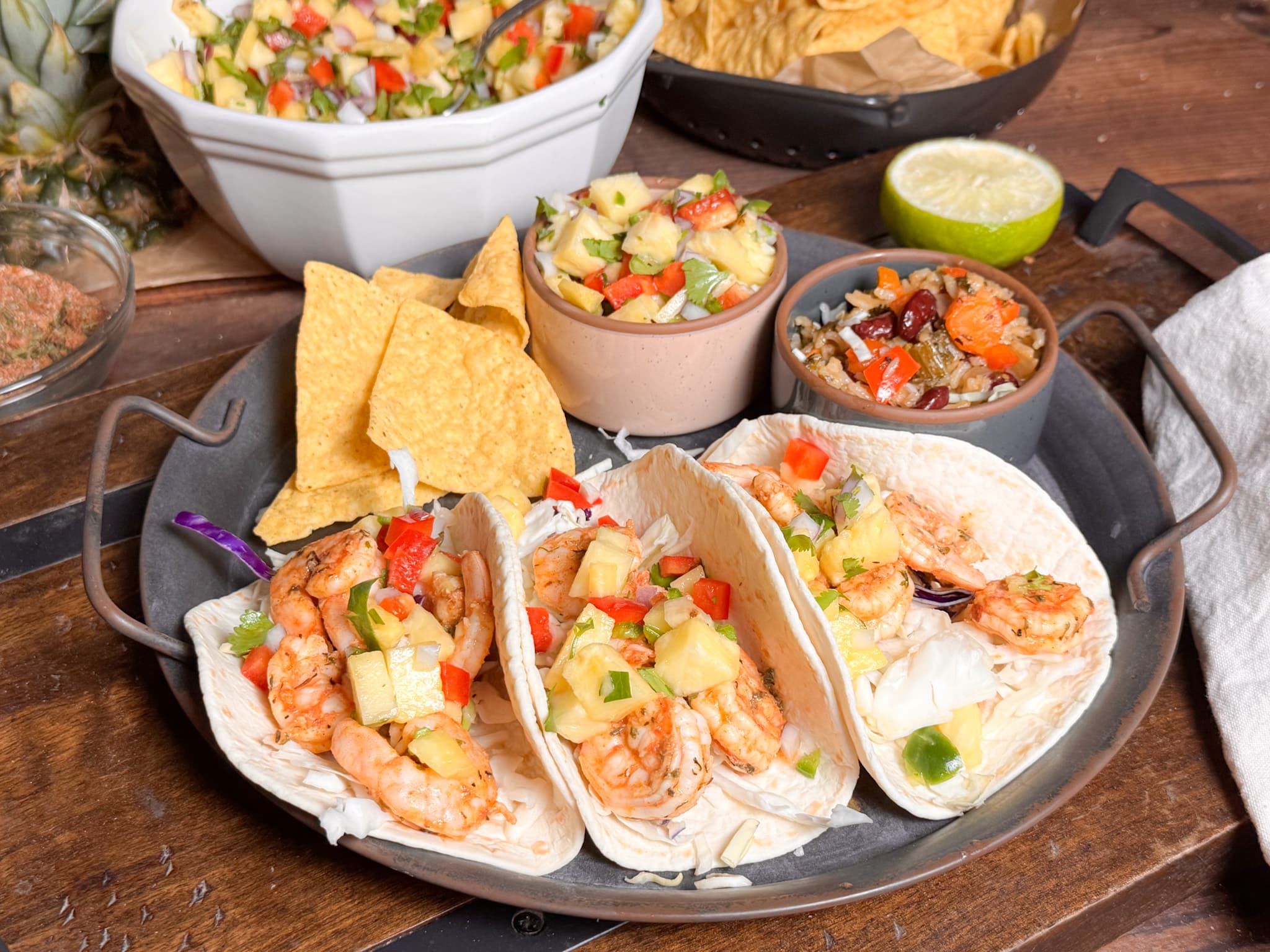 Jamaican Jerk Shrimp Tacos on a Metal Plate with Pineapple Salsa and Jerk Rice in Background