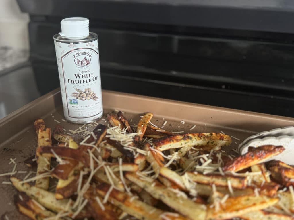 Fries with Truffle Oil and Parmesan on Them with a Bottle of White Truffle Oil