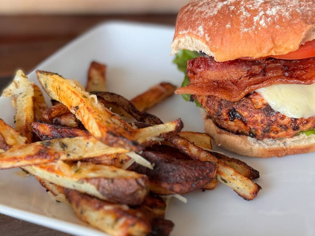 a Pile of Truffle Fries Alongside a Turkey Burger with Cheese and Bacon