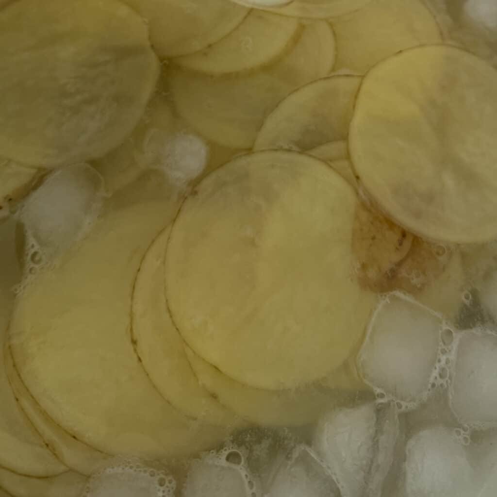 Thinly Sliced Potatoes Soaking in Ice Water