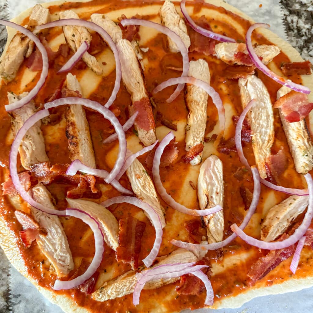 Pizza Sauce, Chicken and Red Onions on Pizza Dough