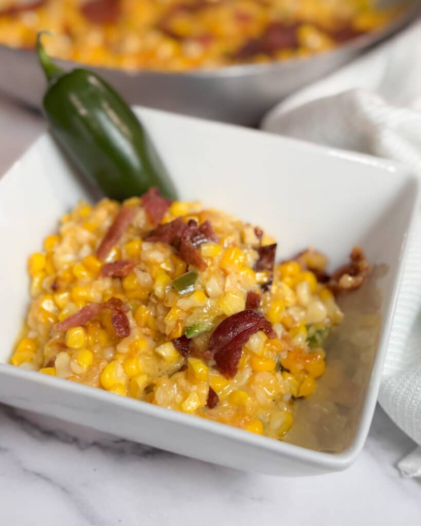 Jalapeño Peach Creamed Corn in a Bowl with a Jalapeño