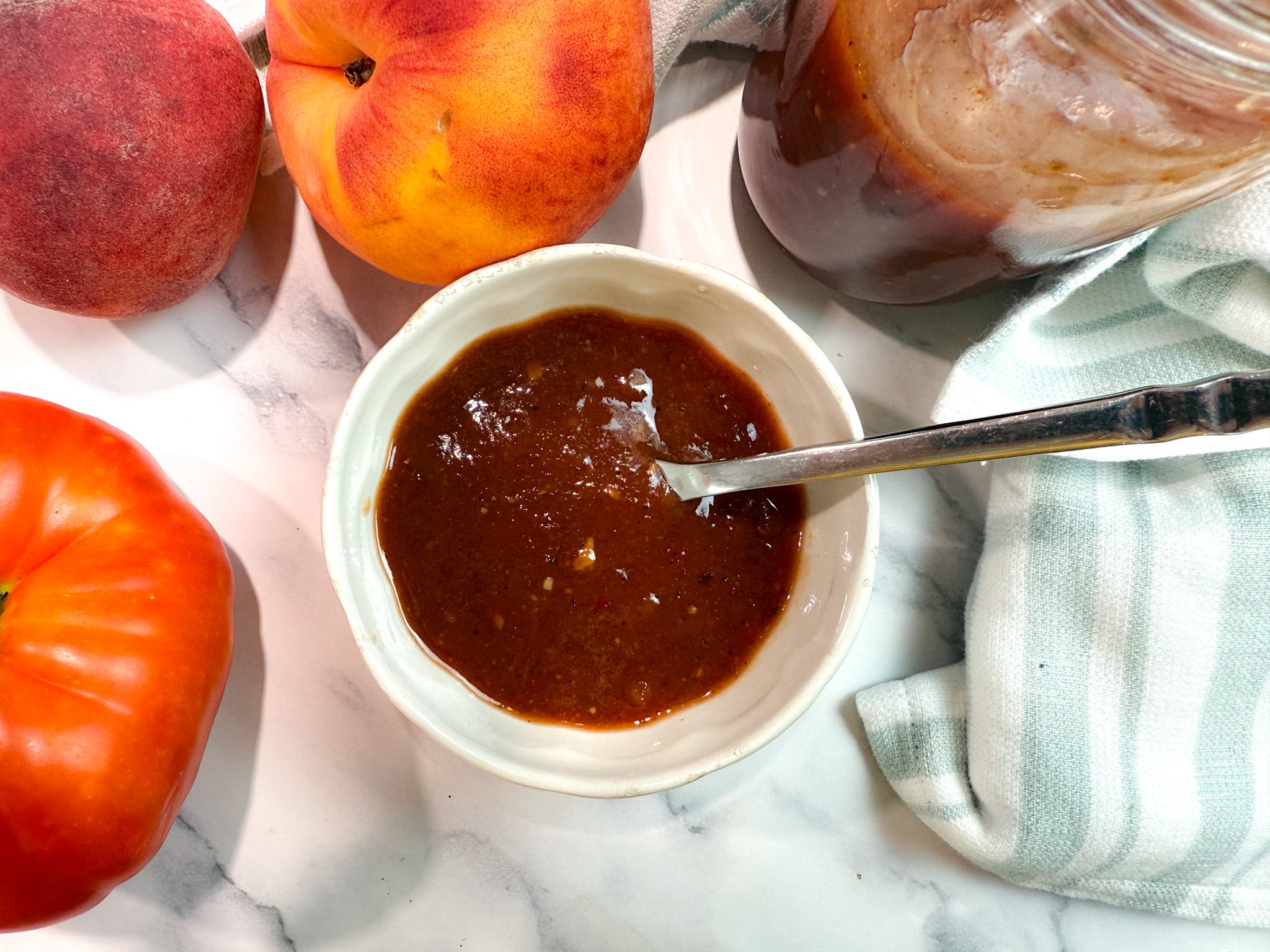 Peach Barbecue Sauce surrounding by tomatoes and peaches