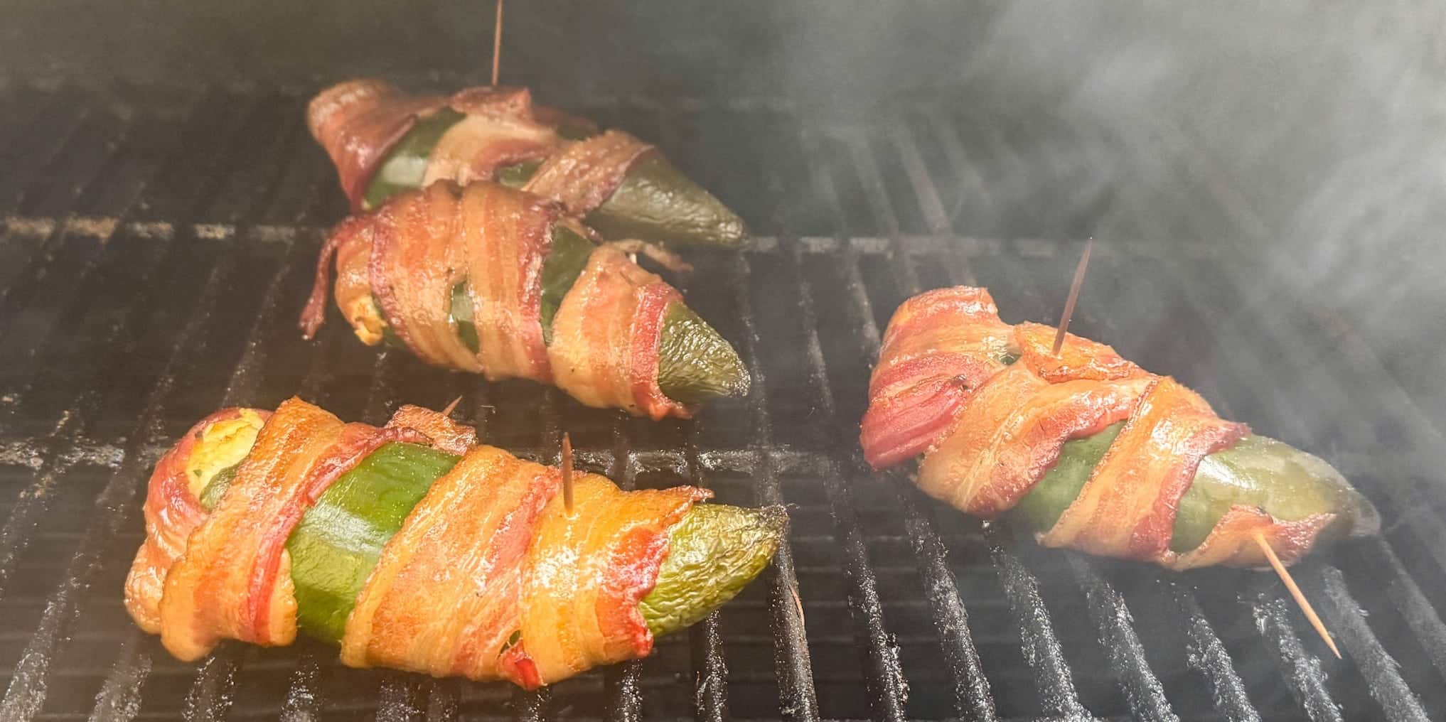 Four stuffed poblano peppers on smoker