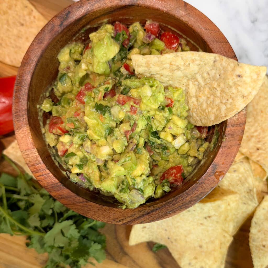 Chunky Guacamole in a Bowl with a Chip