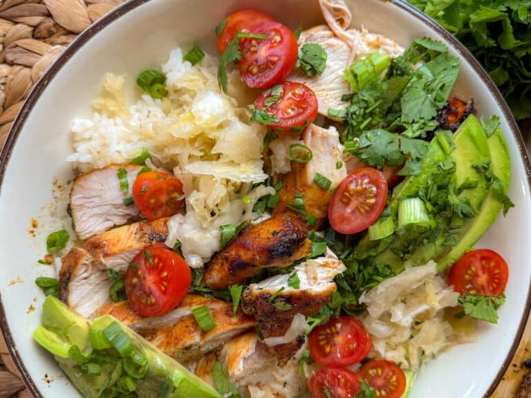 Close Up of a Bowl with Gochujang Honey Garlic Chicken, Sauerkraut, Cherry Tomatoes, Cilantro and Rice